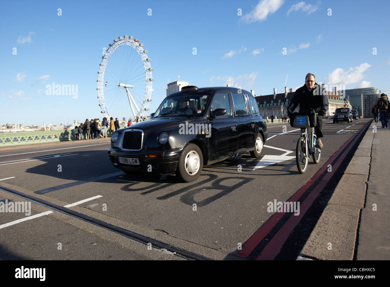 Mann auf gemieteten Zyklus überholt durch schwarzes Londoner Taxi Taxi auf Westminster Bridge in central London England Vereinigtes Königreich Großbritannien Stockfoto