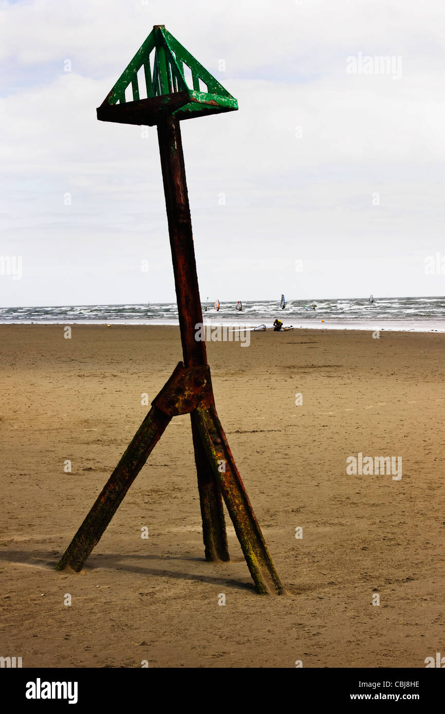 Metall-Flut Warnung Struktur am West Wittering Beach, West Sussex mit Windsurfer im Hintergrund Stockfoto