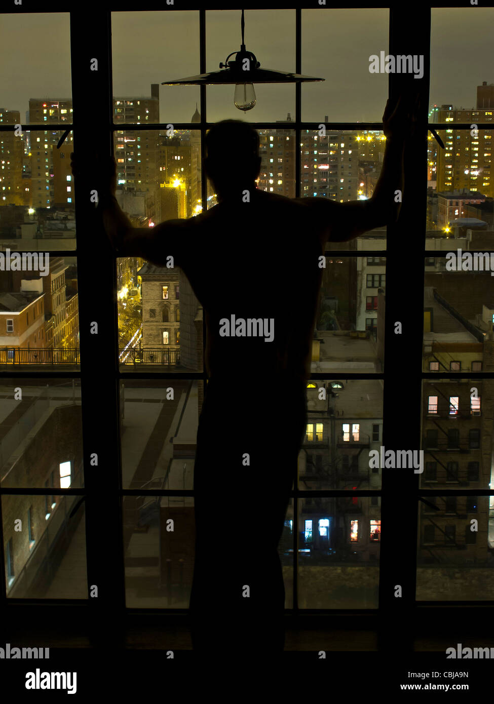 Silhouette der Mann am Fenster in der Nacht mit Blick auf Nw York City, New York, USA Stockfoto