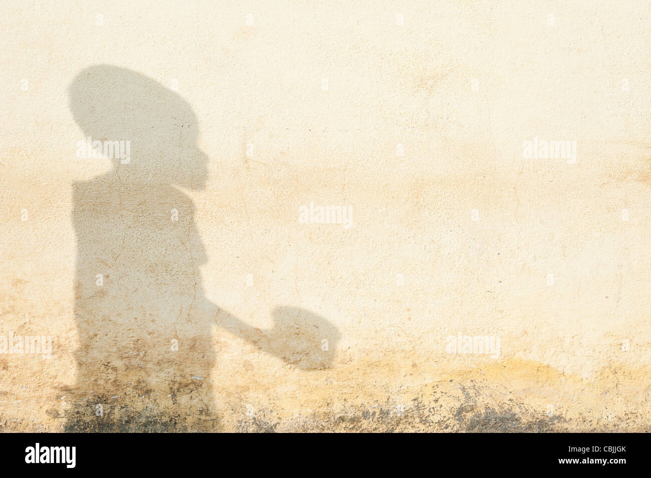 Schatten eines armen indischen Jungen betteln mit einer Schüssel Stockfoto