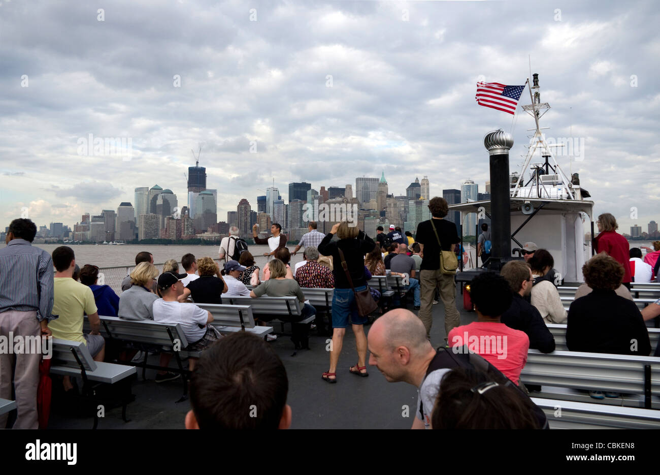 Reisende auf dem oberen Deck der Fähre zurück nach Manhattan nach Fahrt zur Freiheitsstatue und Ellis Island im Hafen von New York City Stockfoto