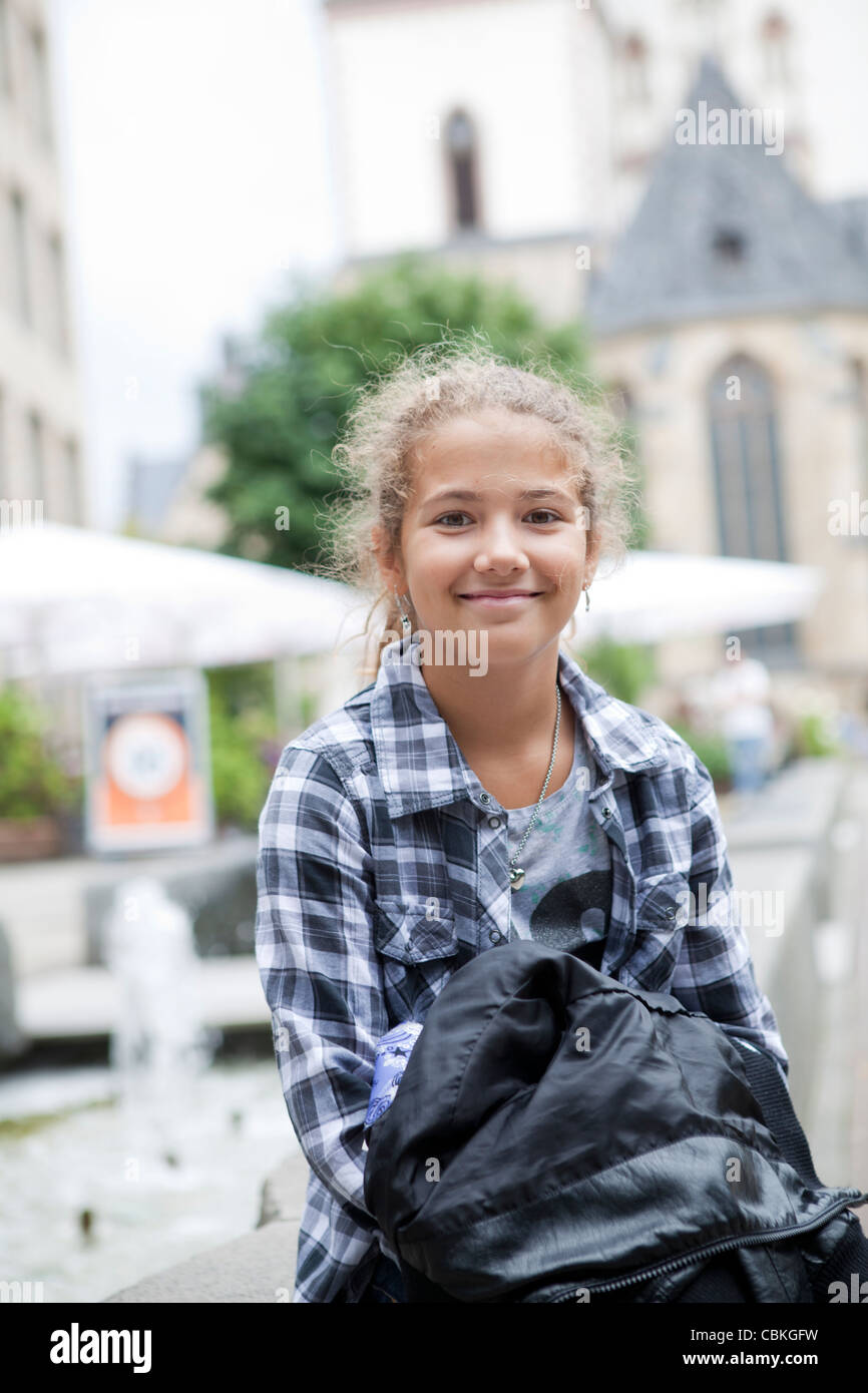 Lächelnd junges Mädchen sitzt am Brunnen im Thomaskirchhof vor St. Thomaskirche in Leipzig, Sachsen, Deutschland Stockfoto
