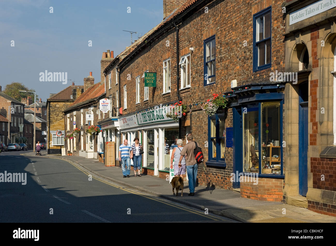 Menschen, die an Geschäften vorbeigehen, Geschäfte Kirkgate Thirsk North Yorkshire England Großbritannien GB Großbritannien Stockfoto