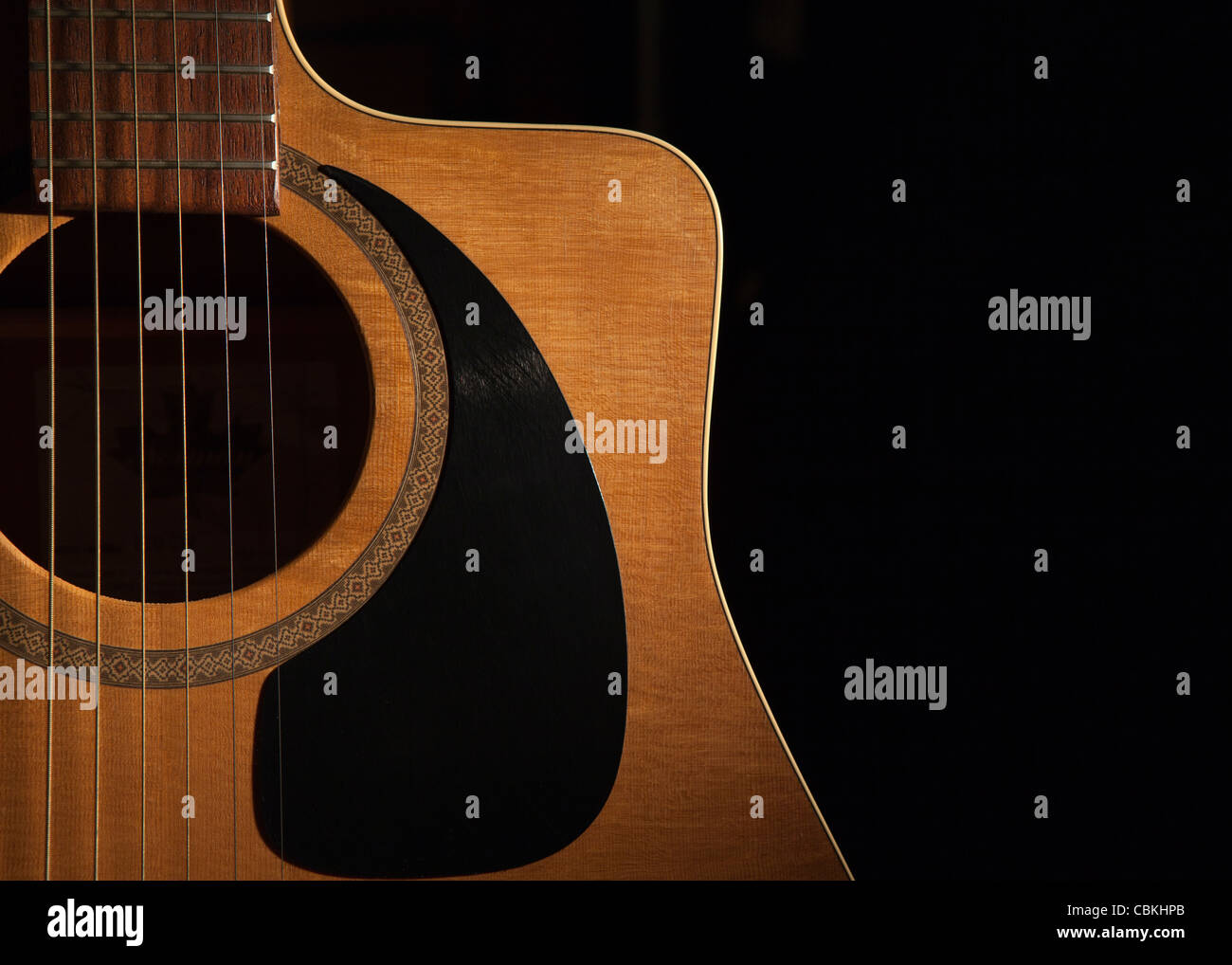 eine Nahaufnahme einer akustischen Gitarre auf einem schwarzen Hintergrund Stockfoto