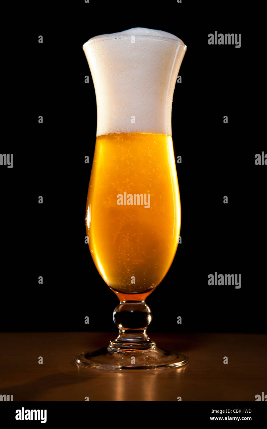 ein blondes Bier in einem stilvollen Glas, breitet sich das Ferment im Glas Stockfoto