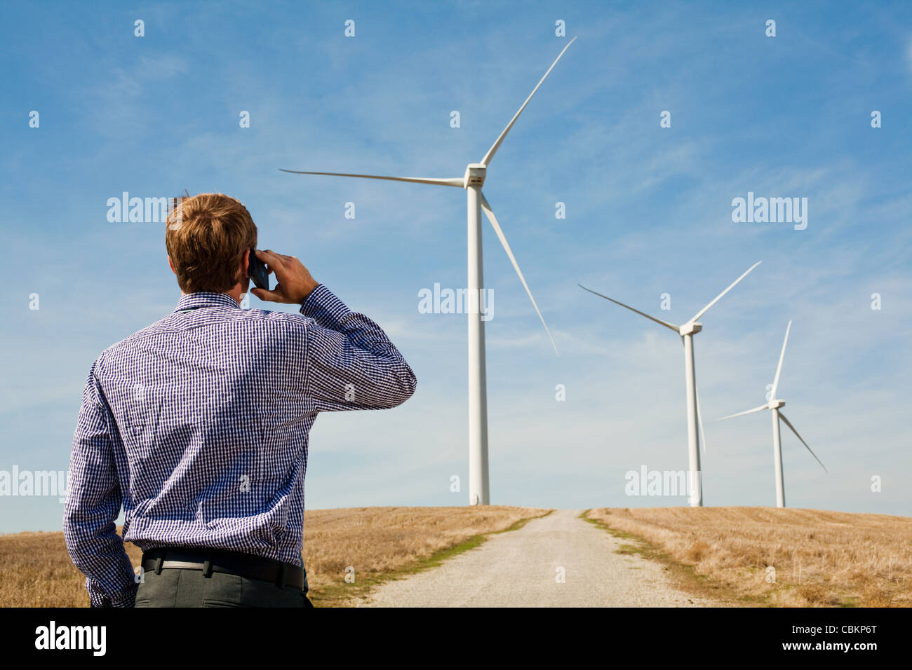 Mann auf dem Handy anschauen Windkraftanlagen Stockfoto