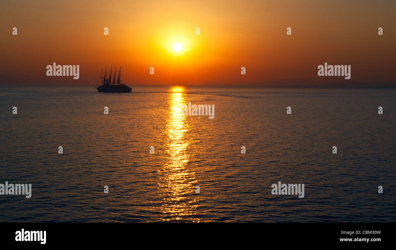 ein Sonnenuntergang auf dem Meer mit einem Segelboot Stockfoto
