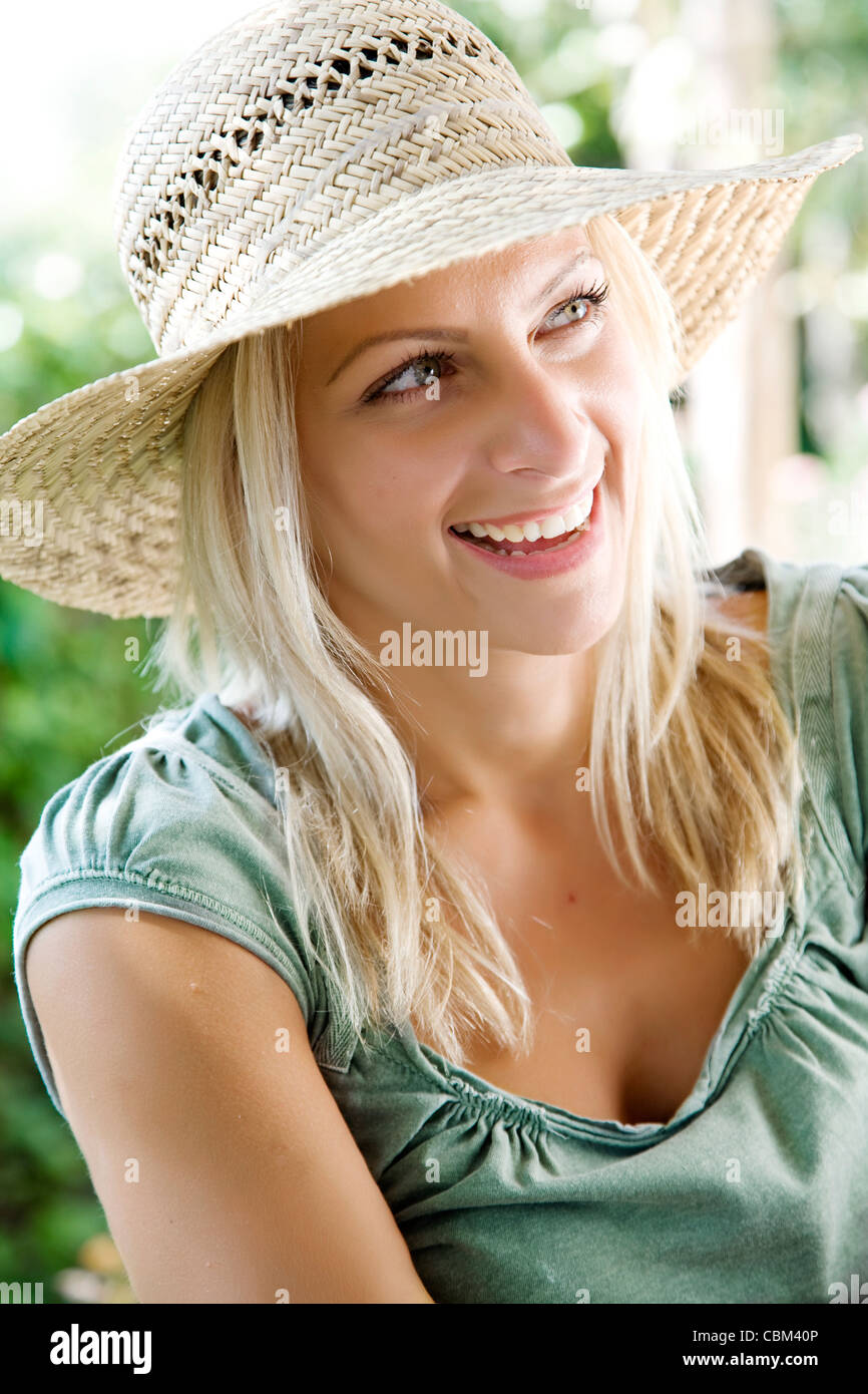 glückliche junge Frau in ihrem Garten Stroh Hut Stockfoto
