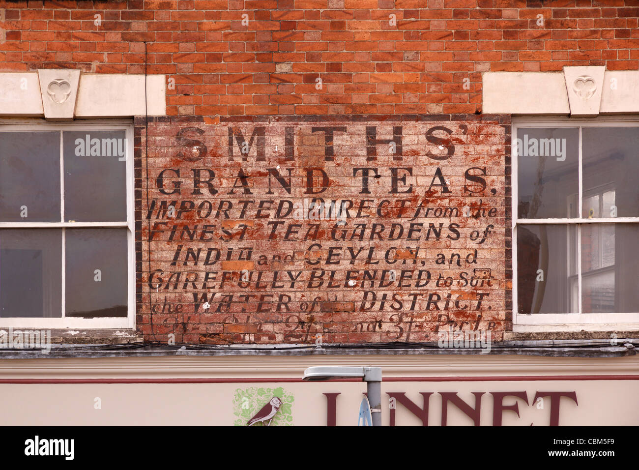 Alten verblichenen bemalten Tee Shop anmelden auf roten Backsteinmauer über laden in Oakham, Rutland, England, UK Stockfoto