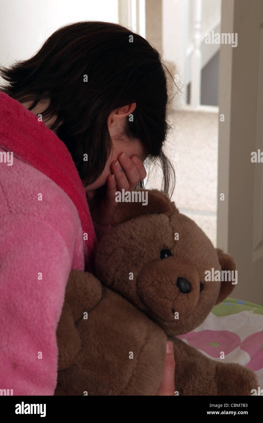 Mädchen trägt einen rosa Bademantel, wischte sich Tränen aus ihren Augen halten einen Teddybär. Stockfoto