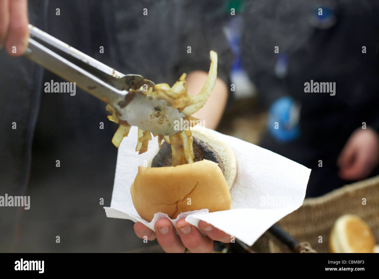 Mann, Zwiebeln in einen Burger in einem Stall in Belfast Nordirland Großbritannien Vereinigtes Königreich Stockfoto