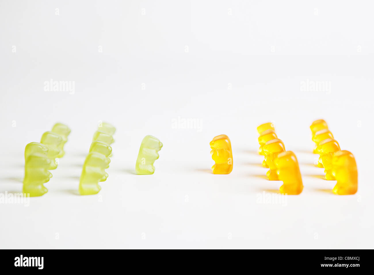 Zwei Reihen von Grün und orange Gummibärchen einander gegenüber, um eine konzeptionelle Botschaft über Führung zu geben Stockfoto