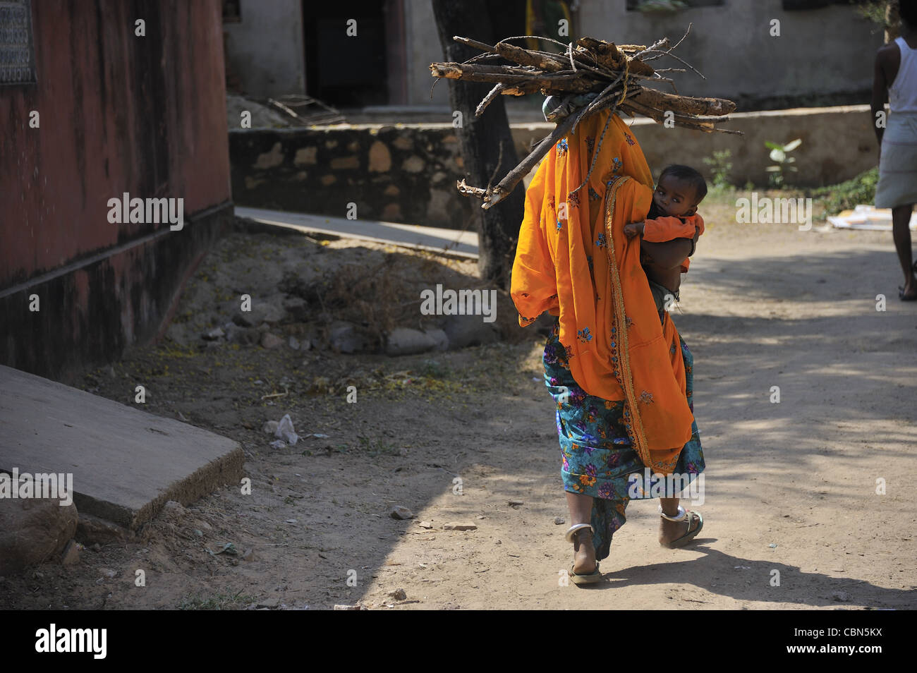 Ein Dorf Frau mit Brennholz und ihr Baby in Indien Stockfoto