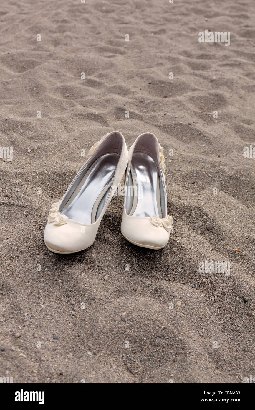 Ein paar Damen Hochzeitsschuhe auf dem Sand am Strand Stockfoto