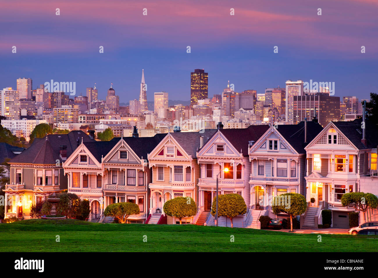 Viktorianische Häuser - die "Painted Ladies" von San Francisco mit der Skyline darüber hinaus in der Dämmerung. Stockfoto