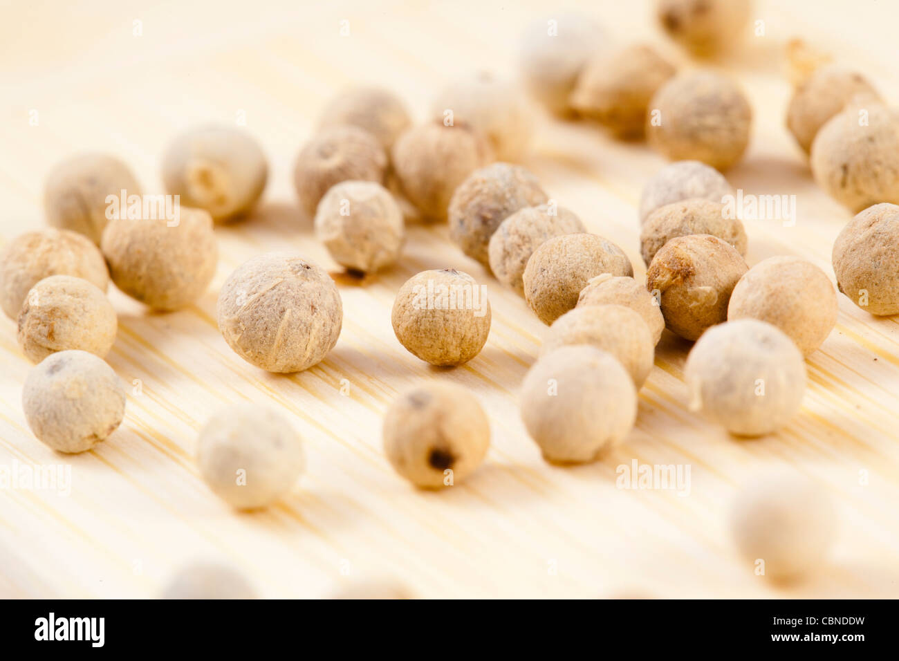 eine Sammlung von weißen Pfefferkörnern auf Holz Stockfoto