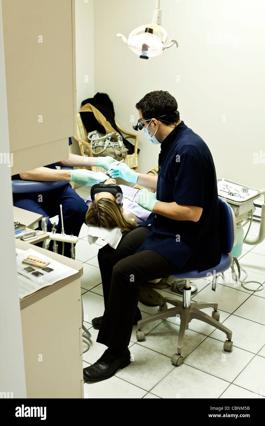 Ein Zahnarzt untersucht Patienten Zähne in seinem Büro in Montreal, Canada.Patient hat die Brille auf einen Film. Stockfoto