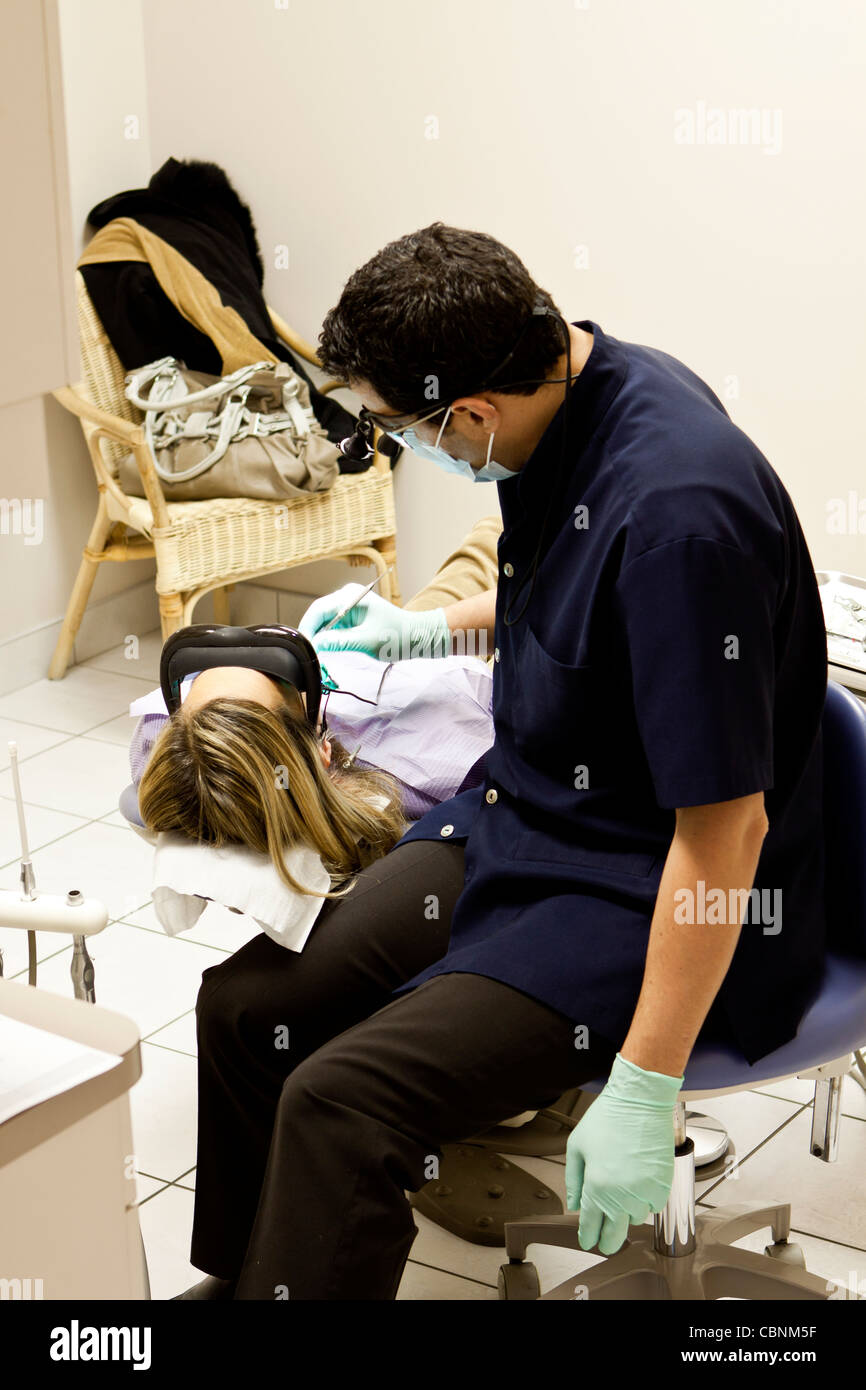 Ein Zahnarzt untersucht Patienten Zähne in seinem Büro in Montreal, Canada.Patient hat die Brille auf einen Film. Stockfoto