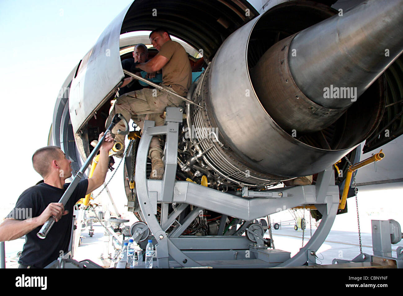 Personal Sgt. Kevin Brown Hände Mitarbeiter Sgt. Jamie Sherwood ein Drehmomentschlüssel als Stab Sgt. Joseph Dodson steht zur Fertigstellung der Installation eines Ersatzmotors auf einem KC-10 Extender Nov. 23. Zwei Tage dauerte es, bis ein Wartungsteam den alten Motor demontieren und den neuen Motor einbauen konnte. Die Sergeanten sind mit dem 380. Expeditionary Aircraft Maintenance Squadron auf einem Luftstützpunkt in Südwestasien. Stockfoto