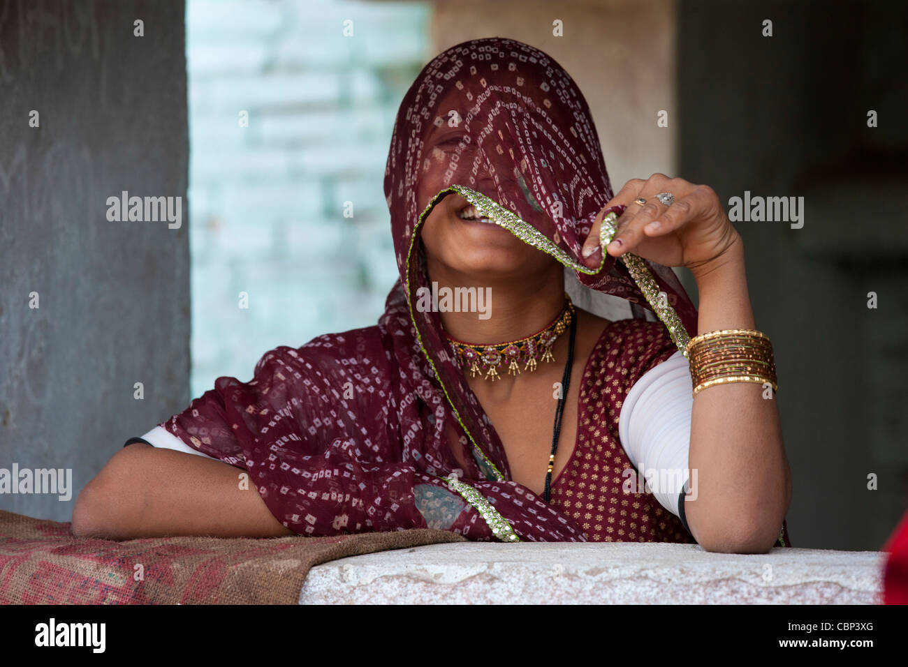 Hübsche junge Inderin bedeckte ihr Gesicht zu Hause in Narlai Dorf in Rajasthan, Nordindien Stockfoto