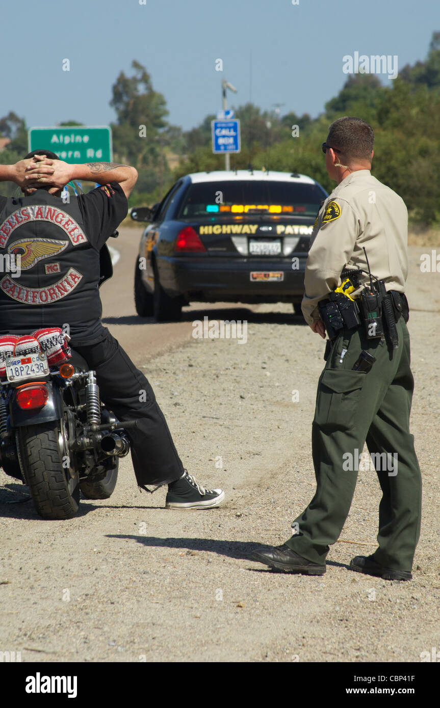 Ein Sheriff Stellvertreter aus dem San Diego Sheriff Department schaut zu, wie ein Mitglied der Hells Angels seine Hände erhoben hat. Stockfoto