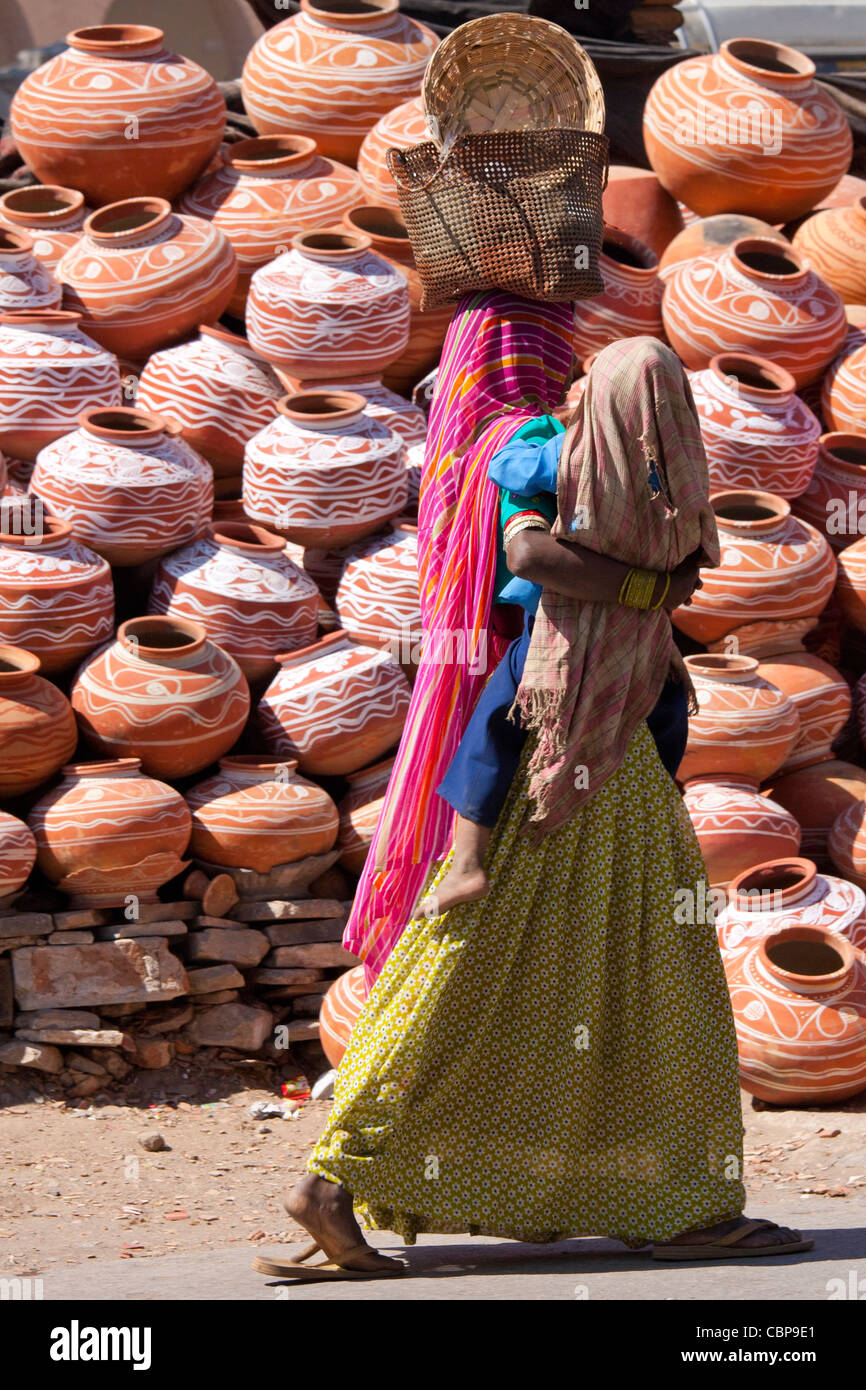 Indische Frau einkaufen mit Kind geht vorbei an Wasser Tontöpfe auf Verkauf in der alten Stadt Udaipur, Rajasthan, Westindien, Stockfoto
