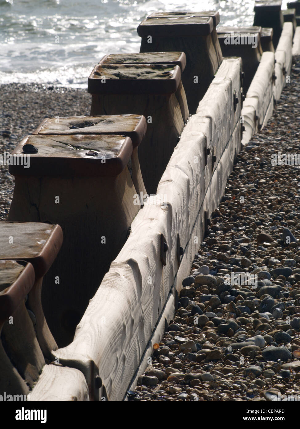 Eine Reihe von Wellenbrecher Beiträge und Holz, die hinunter zum Strands, das Meer gegen die Sonne Stockfoto