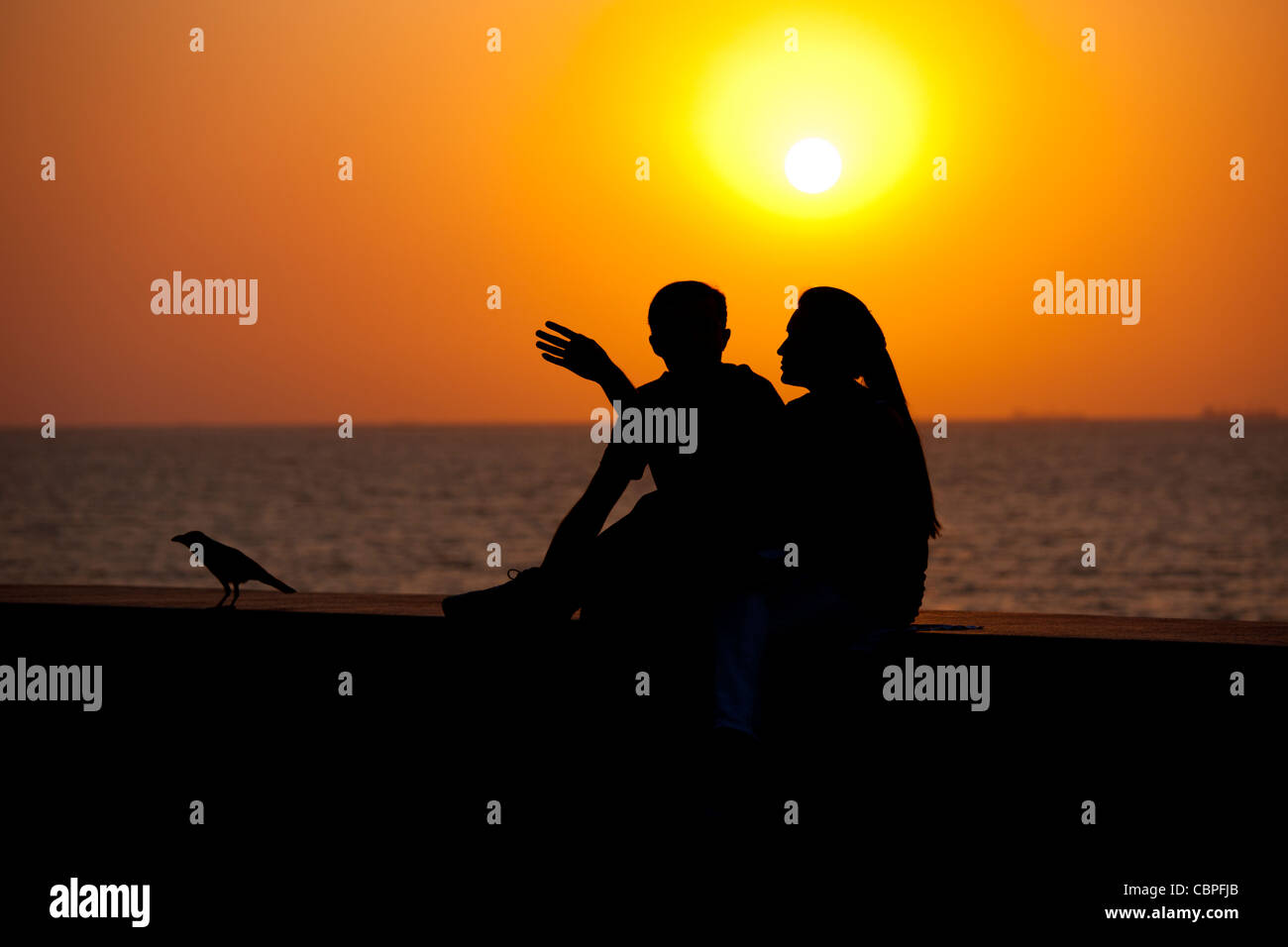 Junge indische Paare sitzen am Deich bei Sonnenuntergang am Nariman Point, Mumbai, ehemals Bombay, Indien Stockfoto