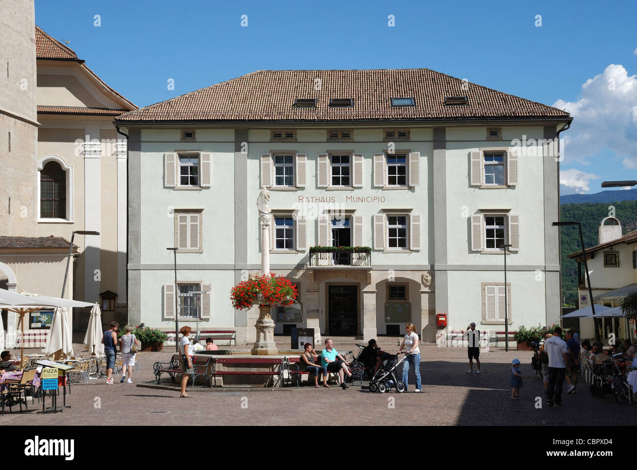 Rathaus von Kaltern an der Südtiroler Wein-Route mit dem Marienbrunnen auf dem Marktplatz. Stockfoto