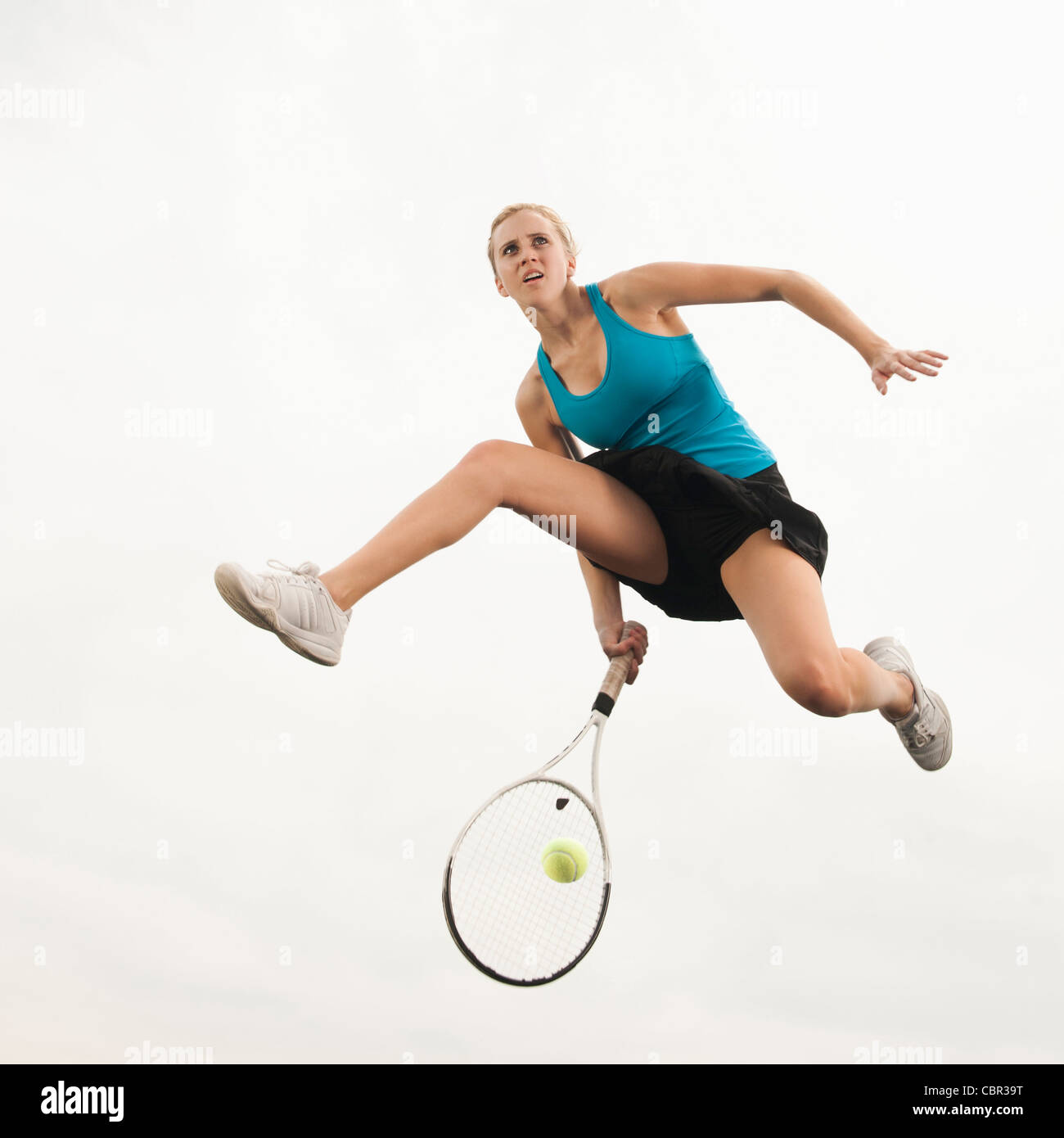 Kaukasische Frau springen in der Luft Tennis spielen Stockfoto