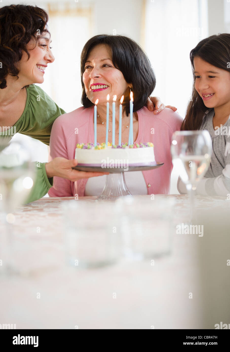 Mutter und Tochter geben Geburtstagskuchen zu Großmutter Stockfoto