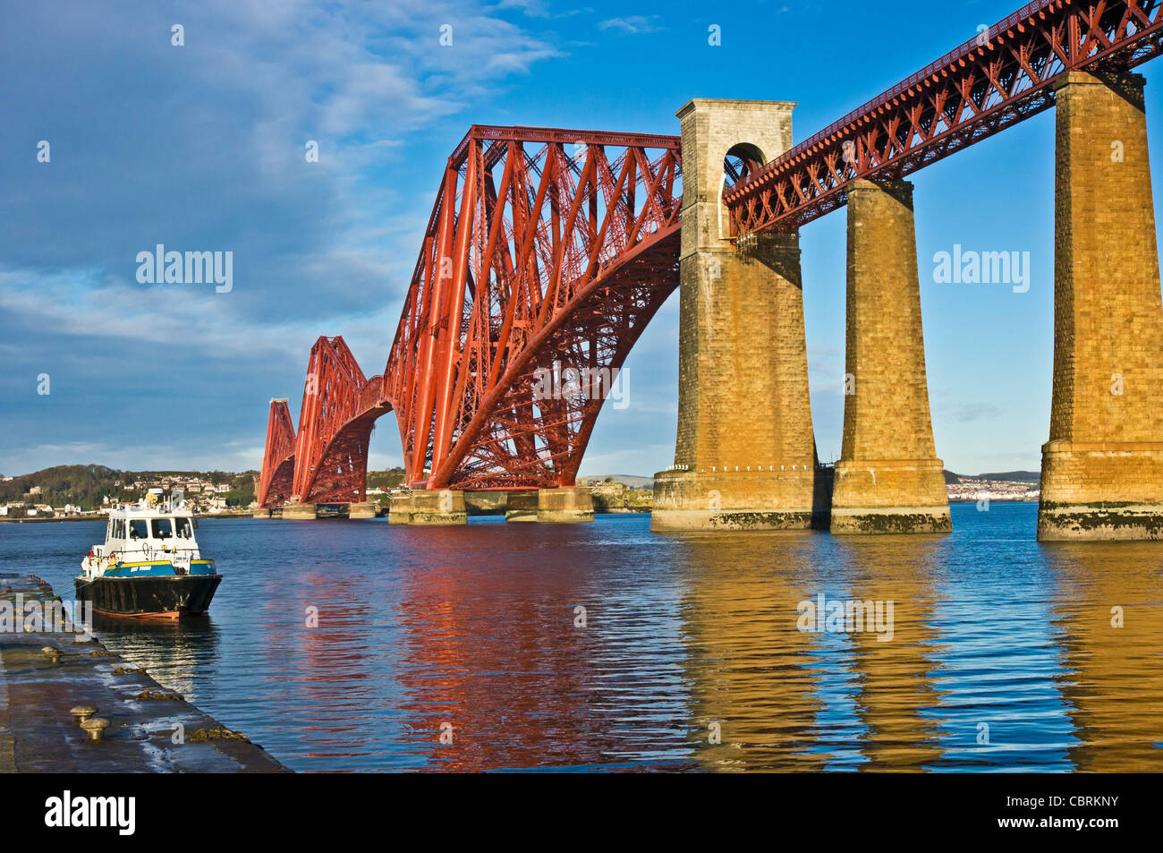 Neu lackiert Forth Rail Bridge gesehen vom Pier am South Queensferry in Schottland mit vertäuten Motorschiff Smit Young Stockfoto