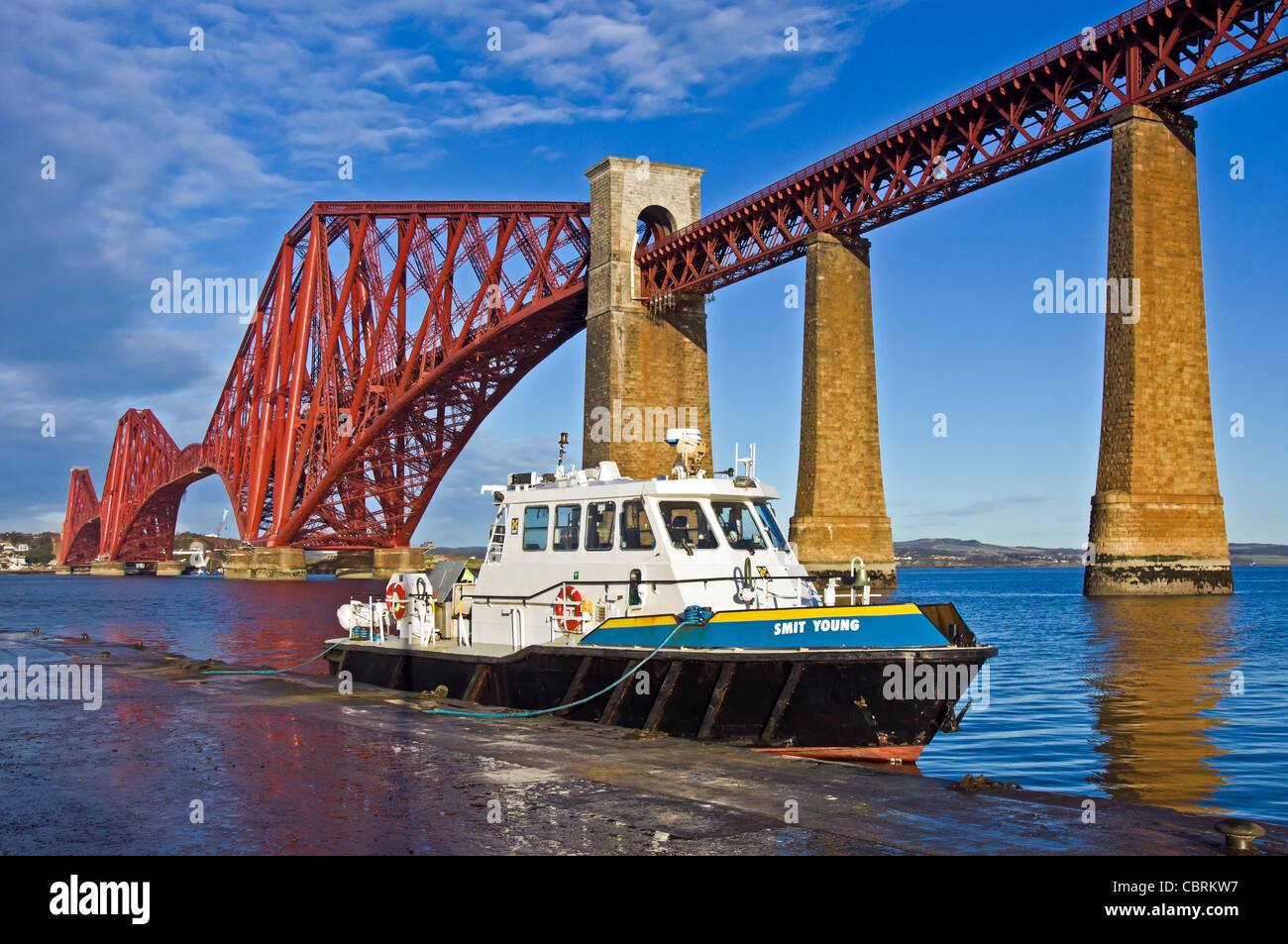 Neu lackiert Forth Rail Bridge gesehen von South Queensferry in Schottland mit vertäuten Motorschiff Smit Young Stockfoto