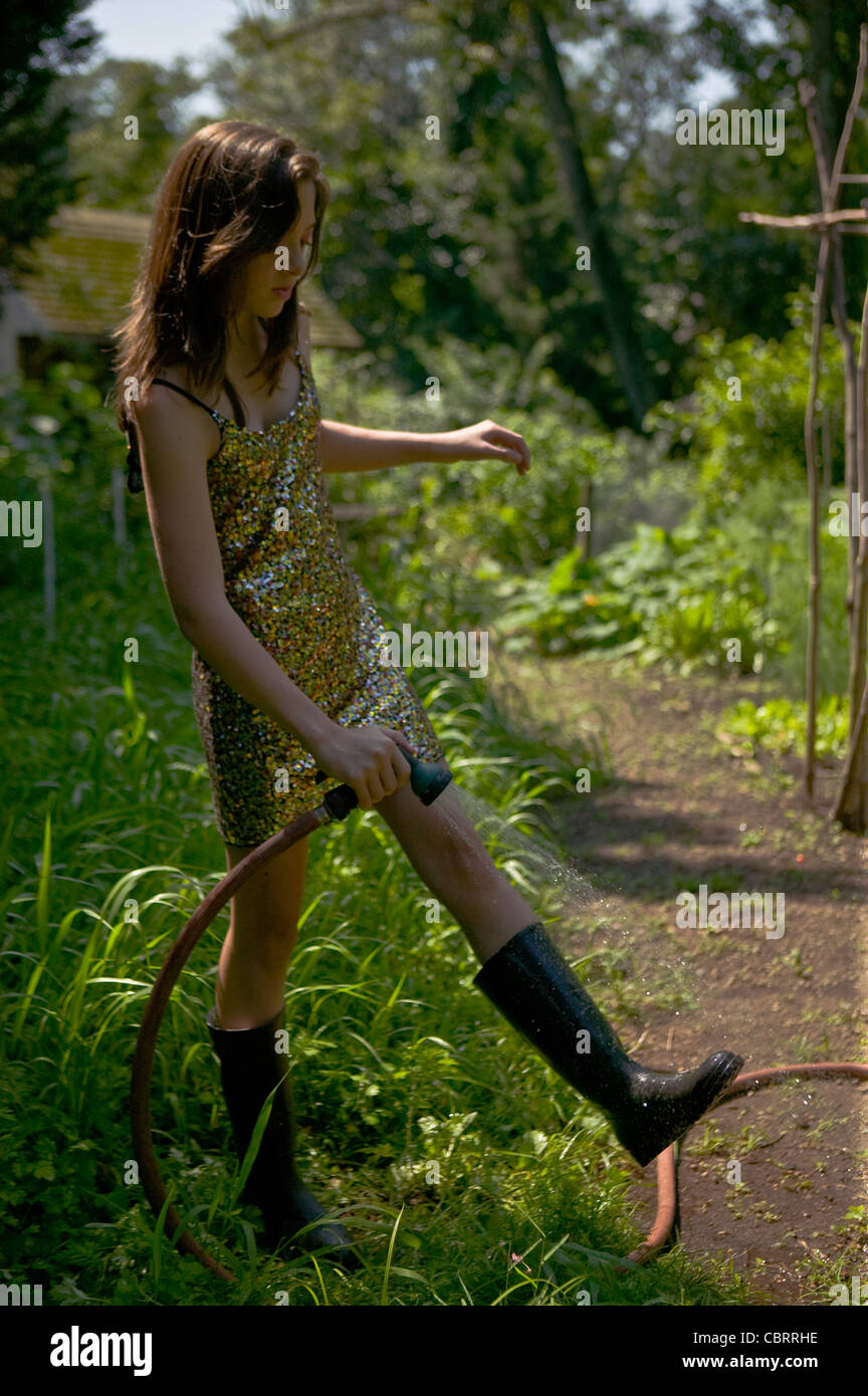 Gartenbewässerung in Pailletten Kleid Mädchen. Stockfoto