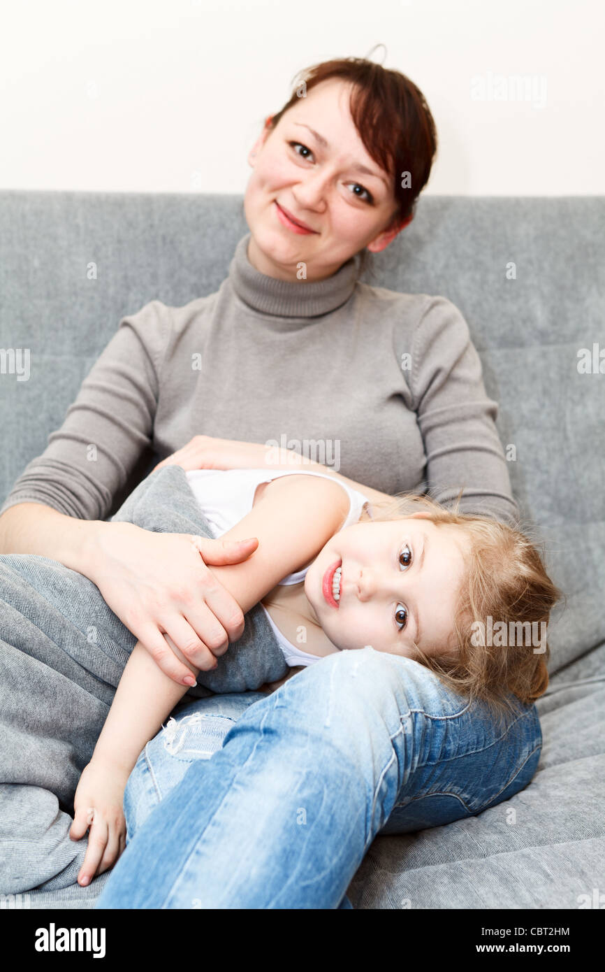 Mutter und ihre kleine Tochter sitzen und Couch und umarmt. Russischen Volkes Stockfoto