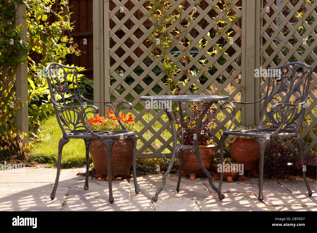 Sonnigen Gartenterrasse mit Spalier und reich verzierten Aluminium Gartenmöbel, England Stockfoto