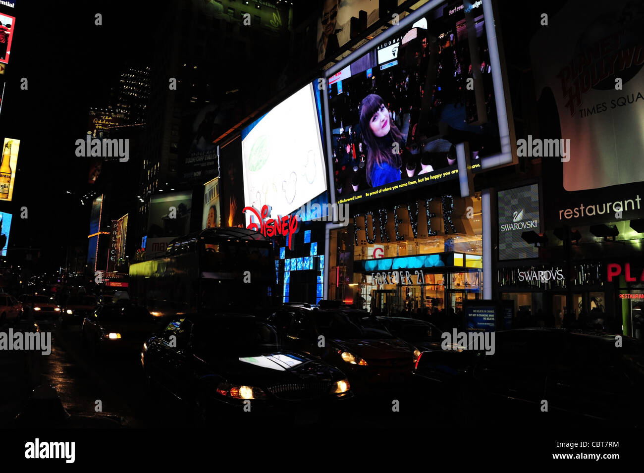 Nächtliche Schrägansicht Verkehr beleuchtet Scheinwerfer vorne Neon LED Fassaden Disney Store, Forever 21, 7th Avenue, New York Stockfoto