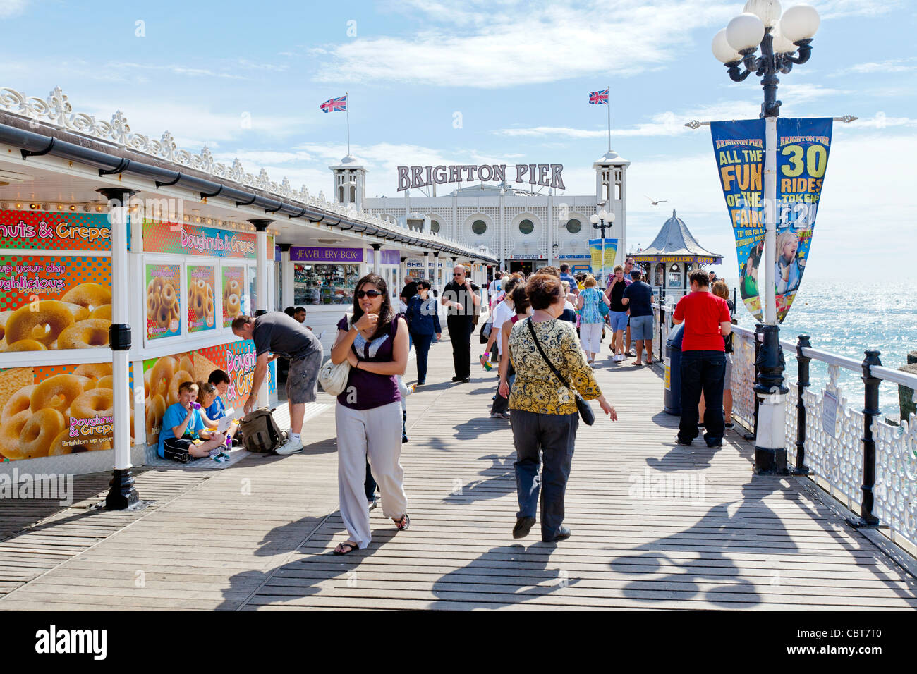 Menschen auf Urlaub und Ferien sitzen, entspannen, Wandern und Vergnügen sich auf der Pier von Brighton Promenade. Stockfoto