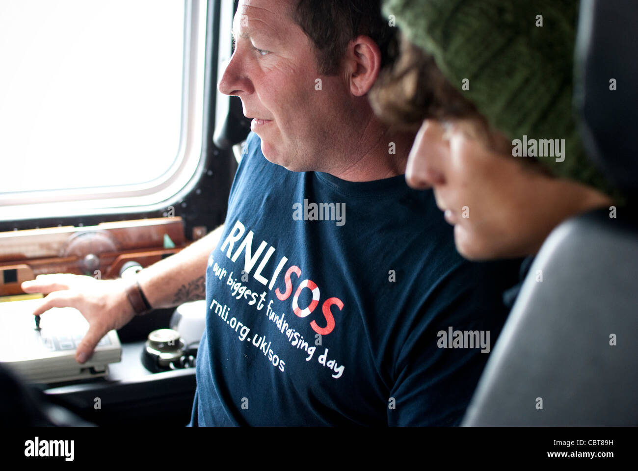 Patch, der Steuermann an das Penlee Rettungsstation zeigt eine Person wie die Steuerung funktioniert. Stockfoto