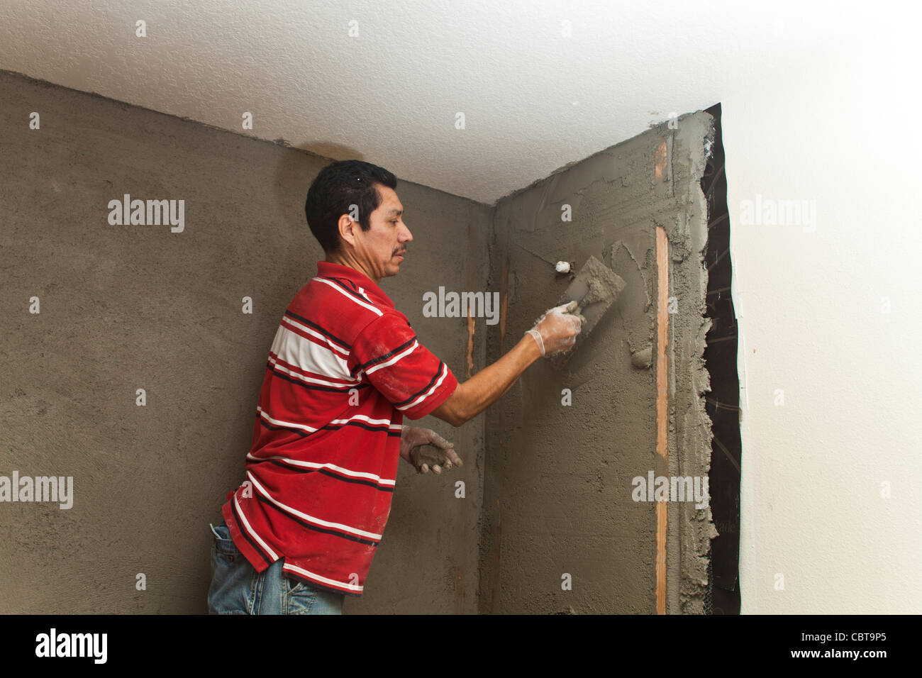 Hispanic Mann aus Mexiko, der sein eigenes Baugeschäft in den USA arbeitet ersetzt Dusche Zement im Gespräch mit Mitarbeiter zu verbreiten. Herr © Myrleen Pearson Stockfoto