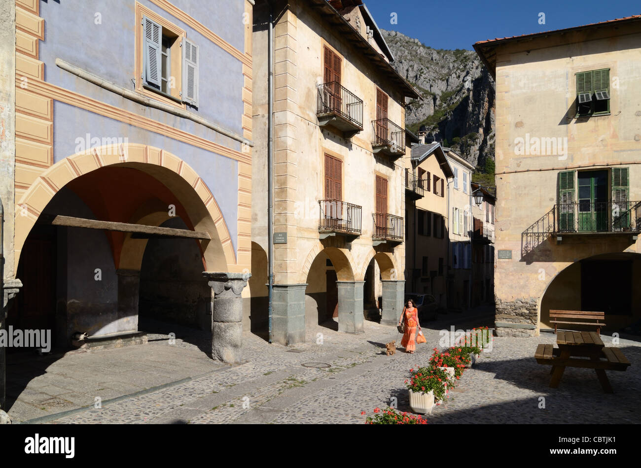 Woman Walking Dog & Street Scene with Arcades, Village Houses and Town Square, La Brigue, Roya Valley, Alpes-Maritimes, France Stockfoto