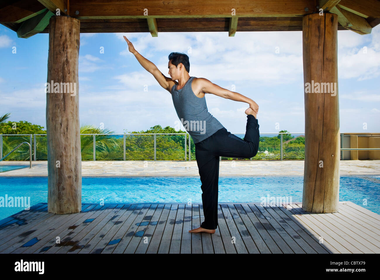 Asiatischer Mann praktizieren Yoga am Pool Stockfoto