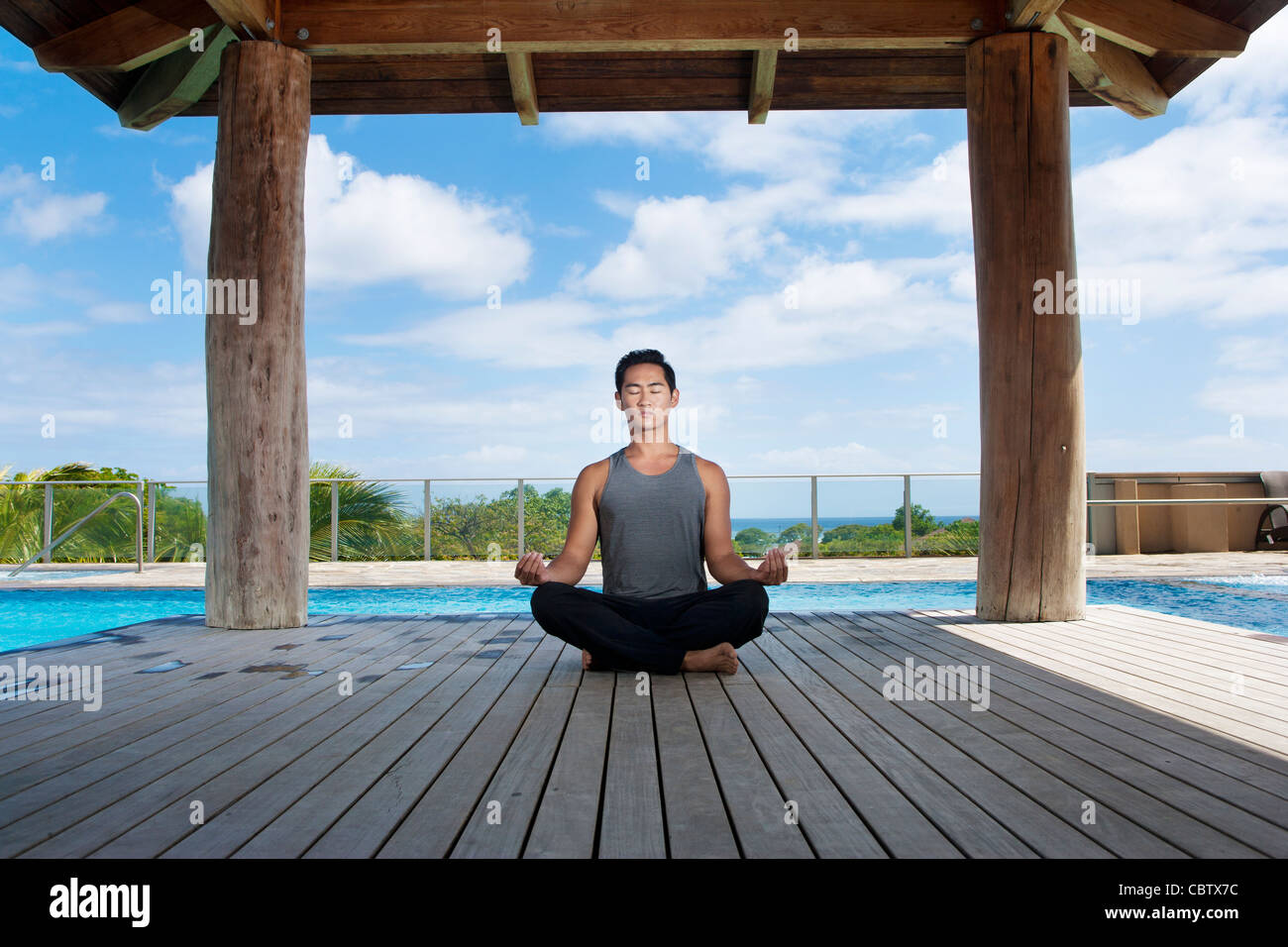 Asiatischer Mann praktizieren Yoga am Pool Stockfoto