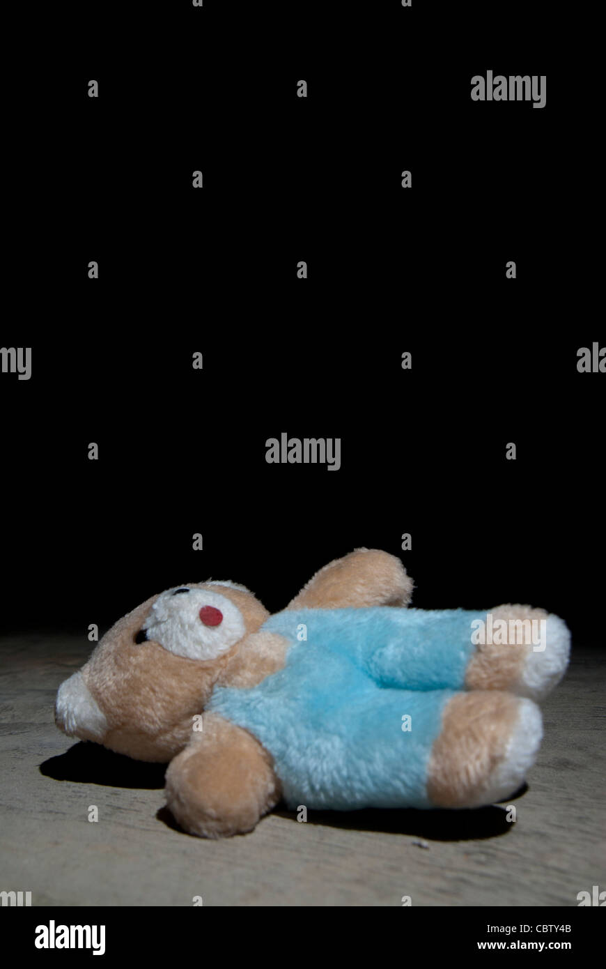 Kind Missbrauch Konzept Bild eines Kindes Teddybären auf dem Boden eines konkreten Raumes Stockfoto