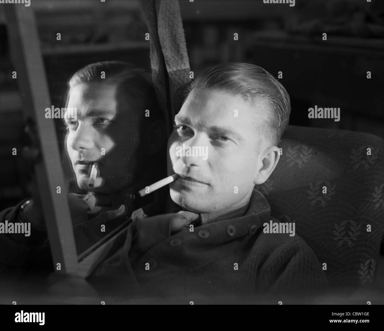 Europa und England während des zweiten Weltkriegs. Debonair amerikanischen GI qualmender Zigarette in Spiegel reflektiert. 1940er Jahre Film Noir Beleuchtung Stockfoto