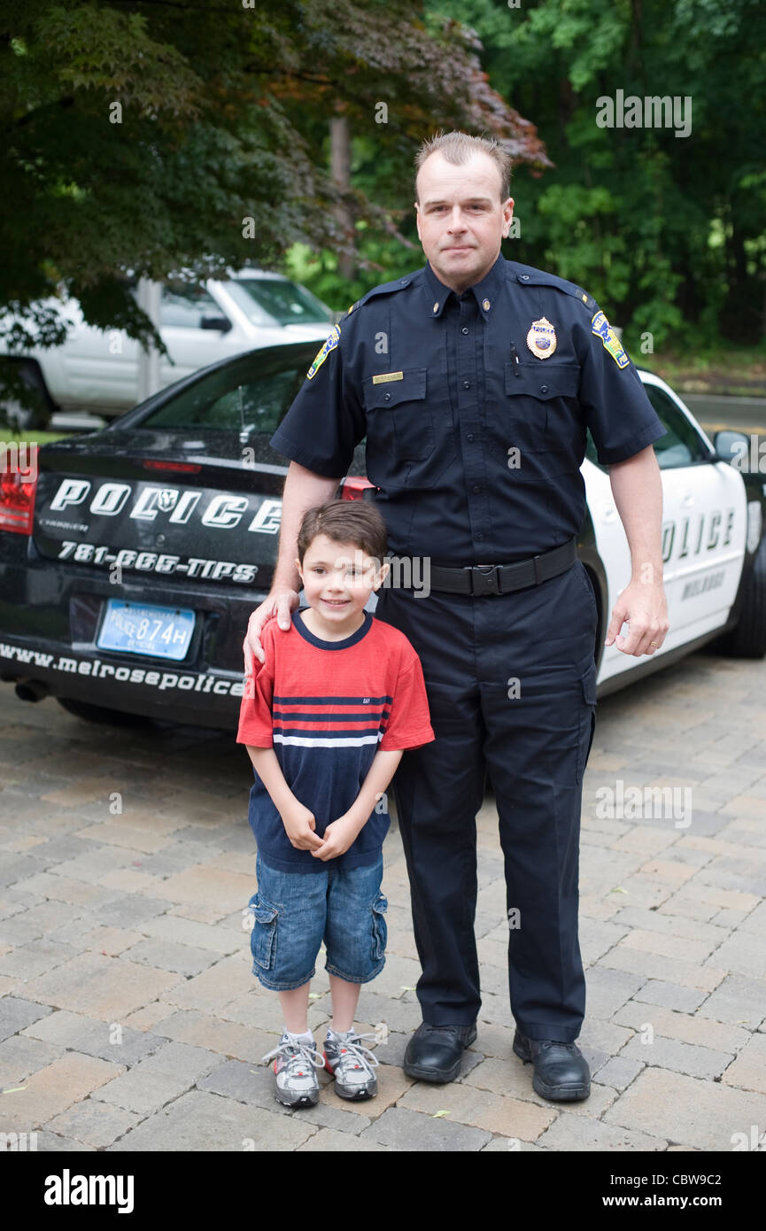 Im Rahmen einer Schule stellt Spendenaktion ein fünf Jahre alter Junge für ein Bild, bevor er eine Fahrt zur Schule in ein Polizeiauto bekommt. Stockfoto