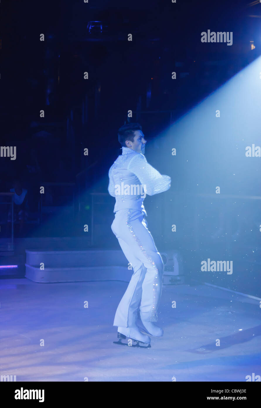 Ein Eis-Skater unter Blaulicht im weißen outfit Stockfoto