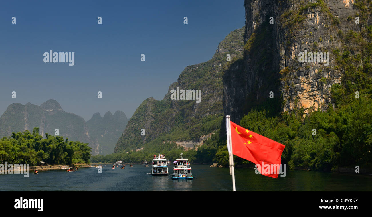 Panorama der chinesischen Flagge und Kreuzfahrtschiffe und Sightseeing Flöße auf dem Lijiang-Fluss Guangxi Peoples Republic Of China mit hohen Karstgebirge Stockfoto