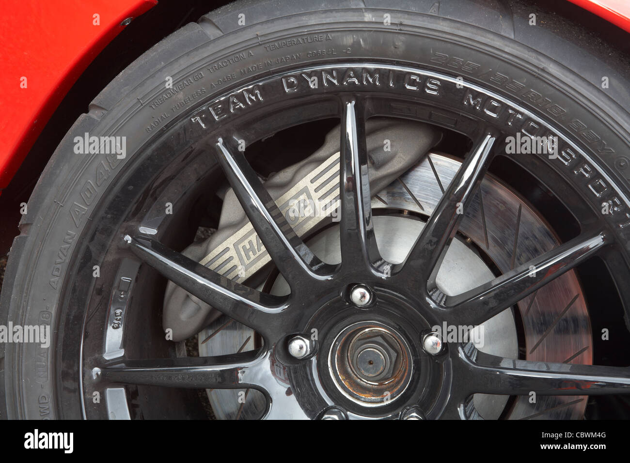 Bremssattel Bremszange und Scheibe Bremsscheibe hinter Metalllegierung Radspeichen auf einem Stromkreis-Rennwagen. Stockfoto