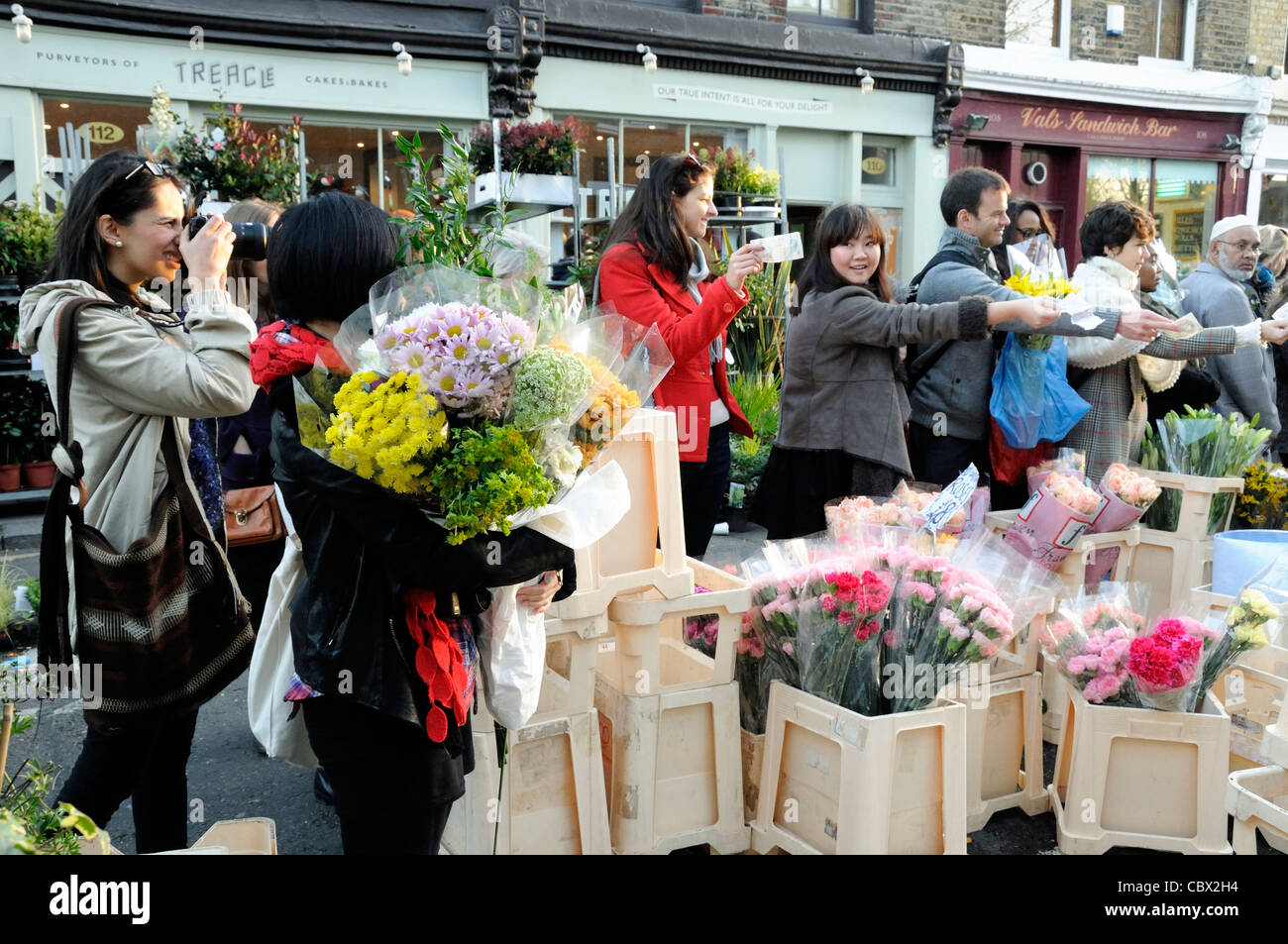 Lady hält mehrere gegründet von Blumen, die aus billig, Columbia Road Flower Market, Tower Hamlet, London UK verkauft werden Stockfoto